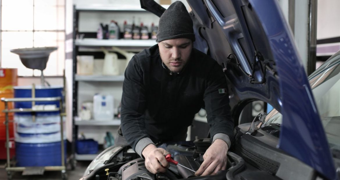 Técnico inspecionando o motor de um veículo com kit GNV durante vistoria