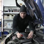 Técnico inspecionando o motor de um veículo com kit GNV durante vistoria